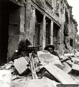 10 juillet 1944 : un soldat armé d’une mitrailleuse posté au milieu des ruines de la ville de Caen. Photo : IWM