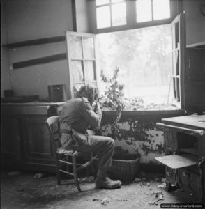 Le soldat anglais Sutcliffe, assis près d’une fenêtre, à la recherche d’éventuels tireurs d’élite allemands dans les ruines de Caen. Photo : IWM