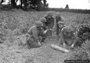 10 juillet 1944 : des sapeurs du Royal Canadian Engineers (R.C.E.) examinent un obus allemand de 155 mm n’ayant pas explosé dans le secteur de Caen. Photo : IWM