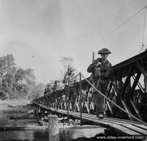 18 juillet 1944 : des soldats du Stormont Dundas and Glengarry Highlanders traversent l’un des ponts Bailey construits par les Royal Canadian Engineers sur l’Orne à proximité de Caen. Photo : IWM