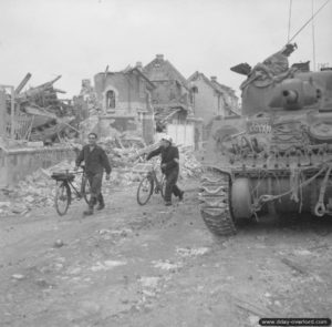 10 juillet 1944 : des habitants de Caen à côté d’un char Sherman au milieu des ruines. Photo : IWM