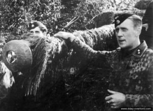 Des Waffen S.S. se tiennent à proximité d’un blindé dan le secteur de Caen. Photo : Bundesarchiv