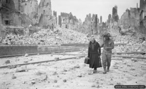 Un soldat anglais apporte son aide à une habitante âgée de la ville de Caen au milieu des ruines. Photo : IWM