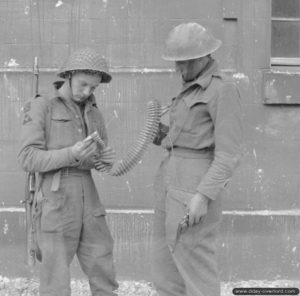 Deux soldats britanniques de la 3rd Infantry Division inspectent une bande de cartouches dans les décombres de Caen. Photo : IWM