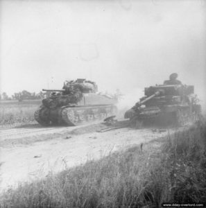18 juillet 1944 : un char Sherman dépasse l’épave d’un char Panzer IV J allemand dans le secteur de Cagny pendant l’opération Goodwood. Photo : IWM