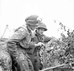 8 juillet 1944 : des officiers du Queen’s Own Rifles prennent des mesures de coordinations en consultant une carte de Carpiquet. Photo : Archives Canada