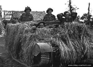 7 juillet 1944 : des soldats canadiens avec un prisonnier allemand de la Luftwaffe à bord d’un Universal Carrier camouflé. Photo : Archives Canada