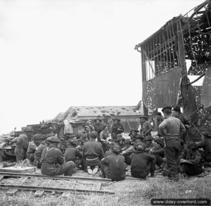 12 juillet 1944 : des troupes canadiennes assistent à un briefing à l’extérieur d’un hangar de l’aéroport de Carpiquet. Photo : Archives Canada