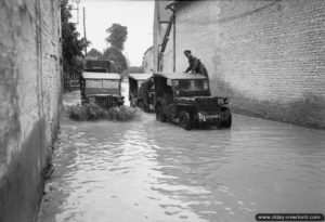 21 juillet 1944 : des Jeeps traversent une rue inondée de la commune de Cully. Photo : IWM