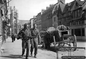 27 août 1944 : des soldats canadiens progressent à côté de deux charrettes allemandes dans les rues de Elbeuf.. Photo : IWM