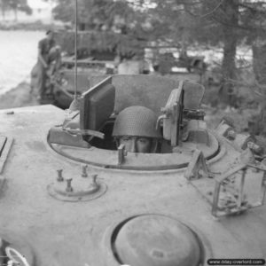 14 août 1944 : le chef de bord d’un char Churchill de la 6th Guards Tank Brigade, prend la pose pour le photographe, assis dans sa tourelle. Photo : IWM