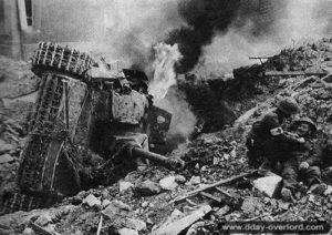 Un soldat canadien blessé est soigné sur l’actuelle avenue du général de Gaulle, à proximité d’un char allemand détruit. Photo : Archives Canada