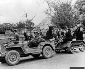 Dans le secteur de Falaise, des soldats Canadiens transportent des civils normands. Photo : Archives Canada