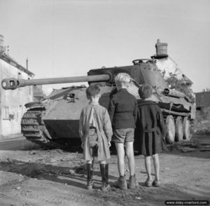 25 août 1944 : trois jeunes normands devant l’épave d’un char Panther allemand. Photo : IWM