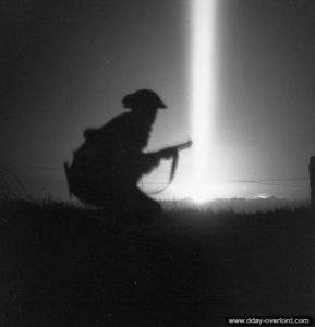 25 juillet 1944 : pendant le tir de barrage de l’artillerie britannique lors de l’opération Spring, un soldat progresse en direction de la ligne de débouché. Photo : IWM