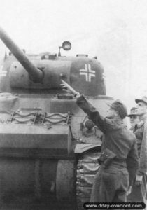 Un char Sherman Firefly ayant appartenu au 148th Royal Armored Corps, 33rd Armored Brigade, est capturé et testé par le Schwere Panzer-Abteilung 503 au nord-est de Giberville. Photo : Bundesarchiv