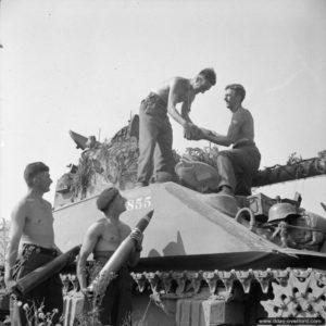 7 août 1944 : l’équipage d’un char Sherman Firefly du 1st Northamptonshire Yeomanry ravitaille en obus avant le lancement de l’opération Totalize dans le secteur d'Ifs. Photo : IWM