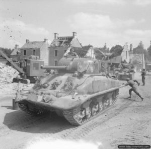 25 juin 1944 : un char Sherman Duplex Drive, traverse Le Douet pendant que des sapeurs déblaient la route. Photo : IWM