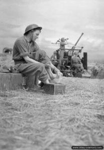 Ernie Hulstone de la Royal Air Force se lave les pieds à proximité d’un canon antiaérien Bofors de 40 mm sur l’aérodrome ALG B-05 de Le Fresne-Camilly. Photo : IWM