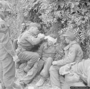 13 juin 1944 : un soldat anglais du Durham Light Infantry, 50th Division, soigne les blessures d’un soldat allemands dans le secteur de Lingèvres