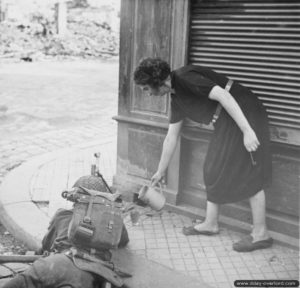 22 août 1944 : une habitante de Lisieux verse du cidre dans le quart d’un soldat armé d’un fusil-mitrailleur Bren. Photo : IWM