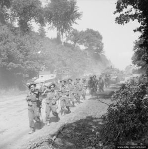 4 août 1944 : de l’infanterie, des half-tracks et des chars Sherman progressent en direction de Vassy à hauteur de Montchamp. Photo : IWM