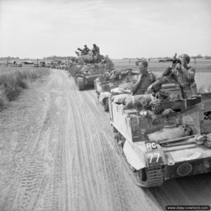 18 juillet 1944 : des Universal Carriers et un char Sherman d’observation d’artillerie progresse dans le secteur de Ranville pendant l’opération Goodwood. Photo : IWM