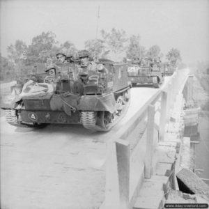 18 juillet 1944 : un Universal Carrier du 1st (Motor) Grenadier Guards, 5th Guards Armoured Brigade, Guards Armoured Division traverse l’Euston Bridge sur l’Orne (renforcé à cet effet) à Ranville dans le cadre de l’opération Goodwood. Photo : IWM