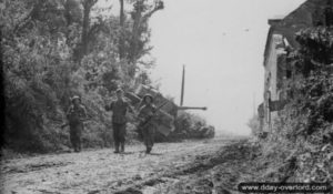 Des soldats allemands prisonniers escortés par des soldats britanniques près du char Tigre « 334 » abandonné dans Rauray. Photo : IWM