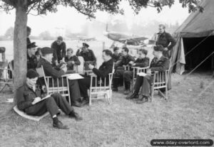 Des pilotes du 168th Squadron marquent une pause abrités sous un pommier de l’aérodrome ALG B-8 de Sommervieu. Photo : IWM