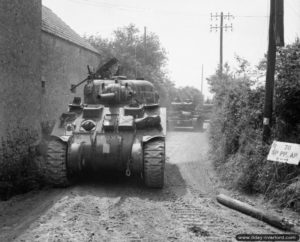 Juin 1944 : un char Sherman et des chars Cromwell progressent dans la localité de Tilly-sur-Seulles. Photo : IWM