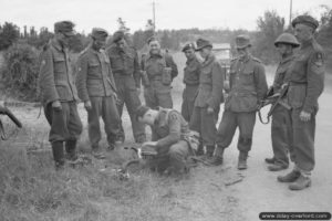 13 juin 1944 : un soldat anglais de la 1st Rifle Brigade inspecte les effets personnels de soldats allemands prisonniers près de Tilly-sur-Seulles. Photo : IWM