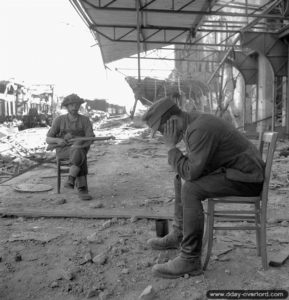 18 juillet 1944 : un soldat canadien garde un soldat allemand fait prisonnier à la gare de Vaucelles. Photo : Archives Canada