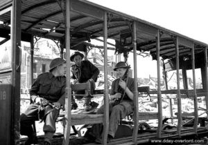 18 juillet 1944 : des soldats canadiens assis dans un autobus détruit à Vaucelles. Photo : Archives Canada