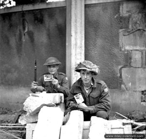 19 juillet 1944 : de gauche à droite, le soldat Norman Milton et le caporal Frank Maxwell à Vaucelles montrent des photos de Dorothy Lamour trouvées dans une tranchée allemande. Photo : Archives Canada