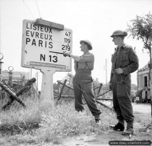 A. K. Jensen et D. Johnston observent un panneau de signalisation couvert de fils électriques dans Vaucelles. Photo : Archives Canada