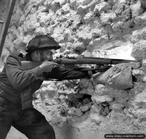 23 juillet 1944 : le soldat R. R. Schwabe du Regina Rifle Regiment observe les environs à l’abri d’un bâtiment de Vaucelles. Photo : Archives Canada