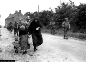 Le 7 juin 1944, des civils normands fuient la zone des combats entre Vierville-sur-Mer et la Pointe du Hoc pendant que les renforts américains se dirigent vers la batterie allemande. Photo : US National Archives
