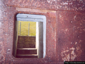 Ouverture blindée pour mitrailleuse, interdisant l'accès à une casemate utilisée comme dortoir pour les militaires de la Pointe du Hoc (2003). Photo : D-Day Overlord