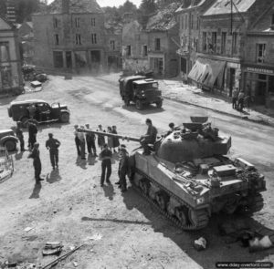 L’équipage d’un char Sherman Firefly installé sur la place centrale est visité par la population de Putanges. Photo : IWM