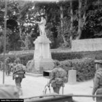 Les soldats du 13th-18th Royal Hussars devant le monument aux Morts d'Hermanville. Photo : IWM