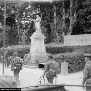 Les soldats du 13th-18th Royal Hussars devant le monument aux Morts d'Hermanville. Photo : IWM
