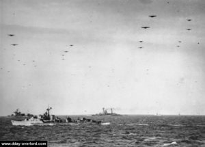 L'HMS Warspite survolé par les avions de transport et les planeurs engagés dans l'opération Mallard dans la soirée du 6 juin 1944. Photo : IWM