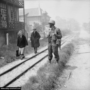 Des civils croisent un MP le long de la voie ferrée à La Brèche. Photo : IWM