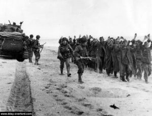 Les prisonniers sont fouillés et guidés vers la plage. Photo : US National Archives