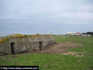 Abri allemand à proximité du point d'appui allemand W5 visible en arrière-plan, à Utah Beach. Photo : D-Day Overlord