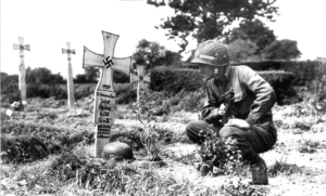 Dans le secteur de Cerisy-la-Salle, le soldat américain Herbert F. Garrettson observe les inscriptions sur la tombe du SS-Grenadier Josef Heinz (6. Kompanie, SS-Panzergrenadier Regiment 38, 17. SS-Panzergrenadier Division), tué le 19 juillet 1944 et enterré à côté d'autres de ses camarades. Photo : US National Archives