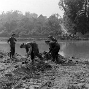 Dans la matinée du 18 juillet 1944, des sapeurs britanniques du Royal Engineers réalisent des travaux de terrassement dans le secteur de Blainville-sur-Orne, le long de l'Orne. Ils préparent la mise en place d'un pont de bateaux qui sera baptisé "Tay 2". Photo : Ralph Morse pour LIFE Magazine