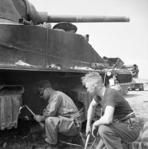 1er août 1944 : dans un dépôt britannique en Normandie où sont stockés des véhicules ne pouvant plus être utilisés, un militaire détache le système de suspension d'un char M4 Sherman à l'aide d'un chalumeau oxyacétylène. Une fois retiré, cet élément servira comme pièce de rechange utilisable par d'autres chars. Photo : IWM B 8408