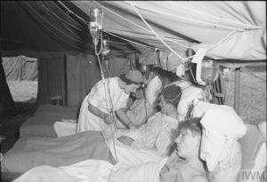 August 15, 1944: A nurse cares for wounded soldiers in a field hospital in Normandy. Photo: IWM B 9222